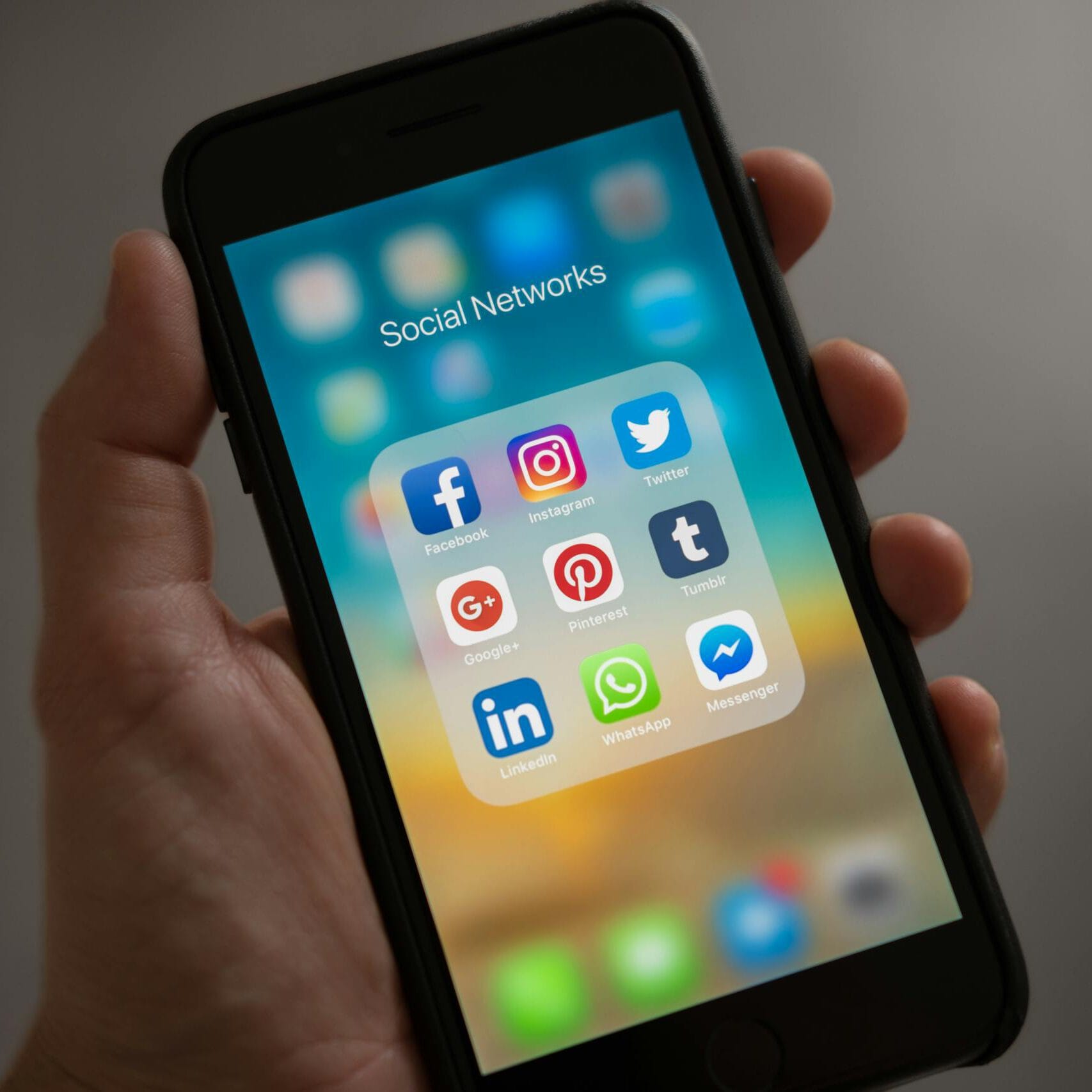 Social marketing. A smartphone displaying various social media icons held in a hand, showcasing modern communication apps.